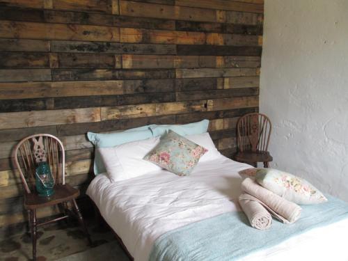 un letto con due sedie accanto a una parete in legno di Lank-gewag Farm Cottage with private hottub a Montagu