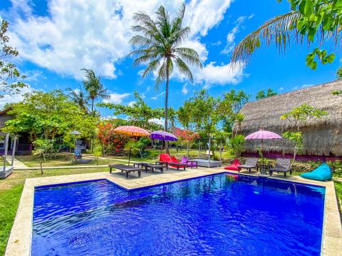 a pool with chairs and umbrellas in front of a house at Namaste Bungalows in Nusa Penida