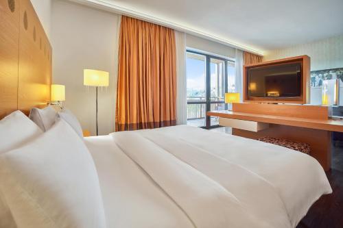 a hotel room with a large white bed and a television at Radisson Blu Resort Bukovel in Bukovel