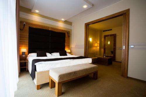 ブラチスラヴァにあるアート ホテル ウィリアムの大型ベッドとベンチ付きのホテルルームです。