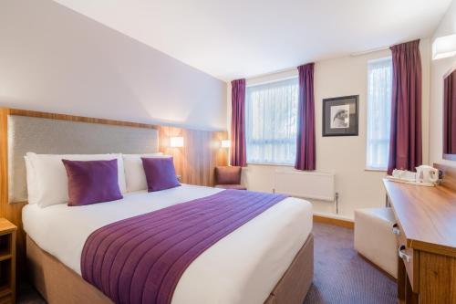 a hotel room with a large bed with purple pillows at Quality Hotel Hampstead in London