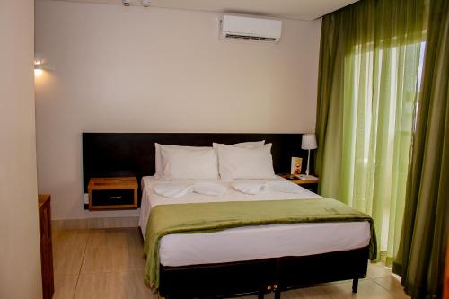 um quarto com uma cama grande e cortinas verdes em HOTEL BARU em Padre Bernardo
