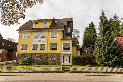 una casa amarilla al lado de una calle en Ski und Biker Hotel Villa Sonnenschein Braunlage am Wurmberg en Braunlage