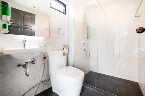 a white bathroom with a toilet and a sink at RoomQuest Sukhumvit36 BTS Thonglor in Bangkok