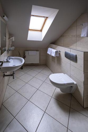 a bathroom with a sink and a toilet and a skylight at Hotel Mario in Lednice