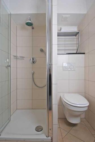 a bathroom with a toilet and a shower with a glass door at Wohlfühlhotel Hörn van Diek Garni mit Schwimmbad in Bensersiel