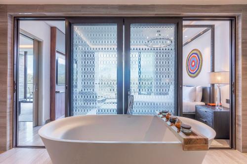 a bath tub in a room with a large window at Gran Melia Arusha in Arusha