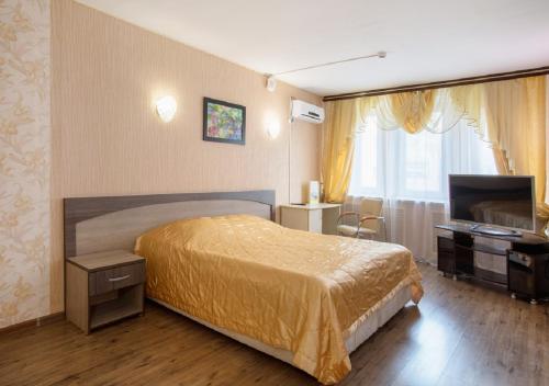 ウラジオストクにあるカルメンのベッドとテレビが備わるホテルルームです。