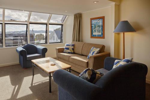 a living room with a couch and two chairs and a table at Pioneer Waterfront Apartments in Paihia