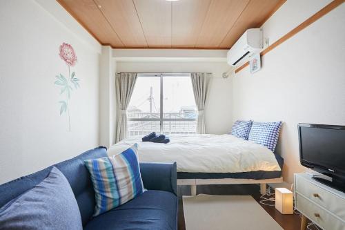 a living room with a blue couch and a bed at Sun white Gyoutoku 303 in Tokyo