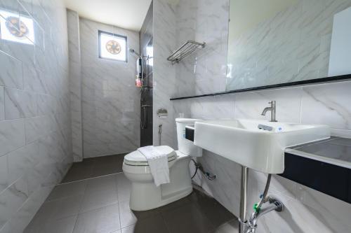 a white bathroom with a toilet and a sink at Top Residence in Suratthani