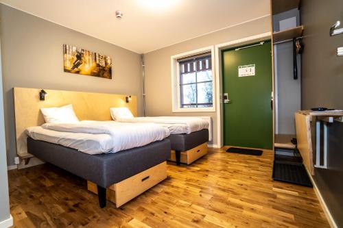 two beds in a room with a green door at JBP Hotell in Järvsö