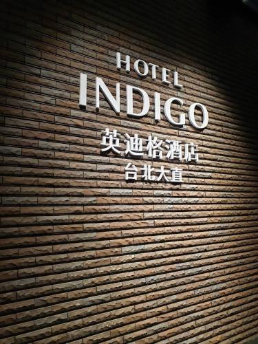 a hotel indigo sign on the side of a brick wall at Hotel Indigo Taipei North by IHG in Taipei