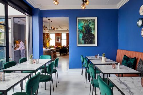 a dining room with blue walls and tables and green chairs at Pineapple House Boutique Hotel in Cape Town
