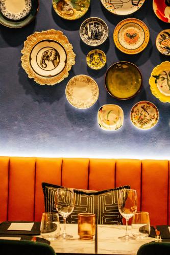 a bunch of plates hanging on a wall above a table at Pineapple House Boutique Hotel in Cape Town