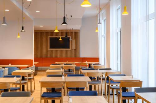 a dining room with tables and chairs and a tv at Holiday Inn Express - Regensburg by IHG in Regensburg