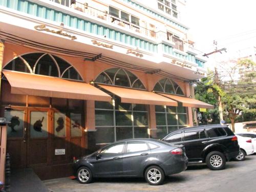 dois carros estacionados em frente a um edifício em Bourbon St. Boutique Hotel em Bangkok