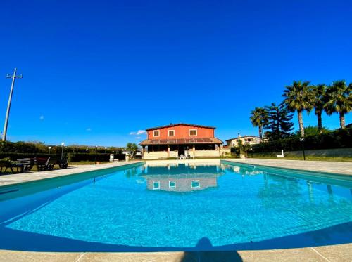 a swimming pool with a house in the background at Villa Stefy apartments in Avola