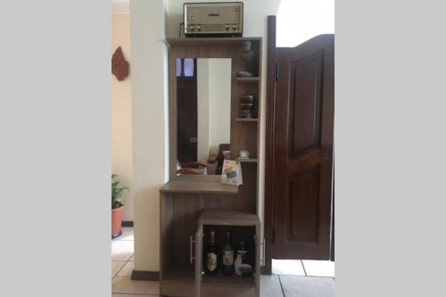 een kamer met een spiegel en een plank met flessen bij Confortable mini departamento in Loja