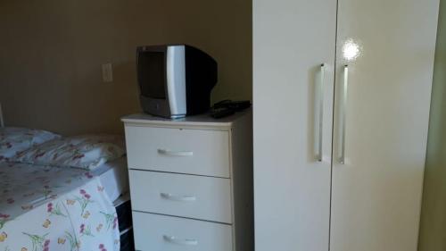 a tv on top of a dresser with a bed at Menina da Lua in Rio das Ostras