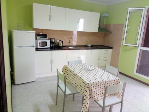 a kitchen with a table with chairs and a white refrigerator at Moradia Cor de Rosa in Machico