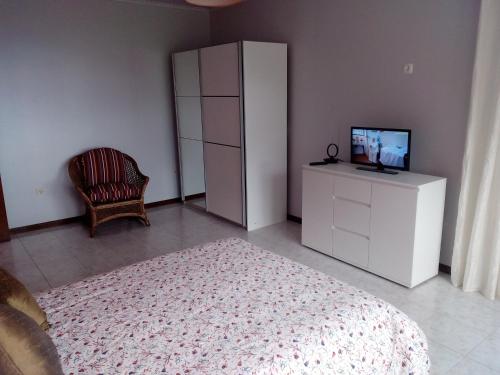 a bedroom with a white cabinet and a tv and a chair at Moradia Cor de Rosa in Machico