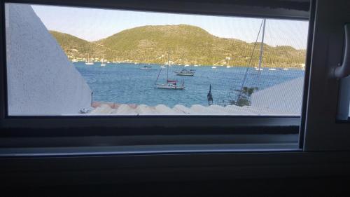 a window view of a bay with boats in the water at Ola Kala Apartments and Rooms in Vlikhon