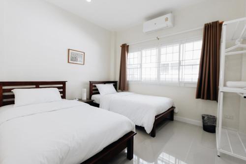 a hotel room with two beds and a window at Glass House, Mountain View, Near Airport-City in Chiang Rai