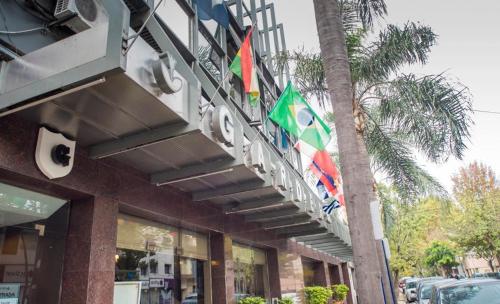 a building with flags hanging from a palm tree at Hotel Garden in Rosario