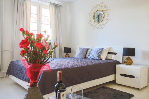 a bedroom with a bed and a vase with red flowers at Republika Kopernika Apartment in Toruń