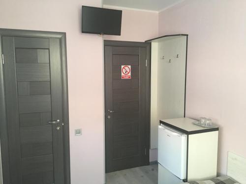 a bathroom with two doors and a television on the wall at Guest House MAX in Khmelʼnytsʼkyy