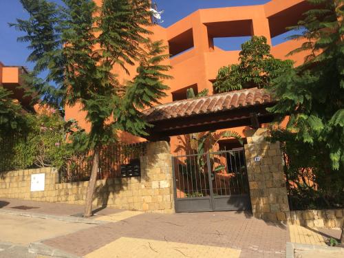 un edificio naranja con un árbol delante de él en Beautiful apartment in Costa del Sol,300m from sea, en Estepona
