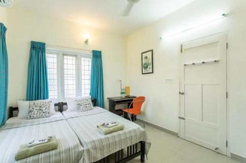 1 dormitorio con 1 cama con cortinas azules y escritorio en The Pod Cochin Homestay, en Kochi