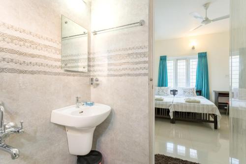 a bathroom with a sink and a bedroom with a bed at The Pod Cochin Homestay in Cochin