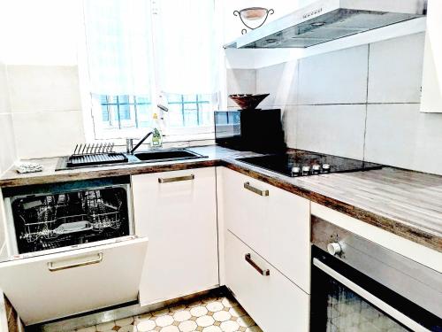 une cuisine avec des armoires blanches et un four à plaques de cuisson dans l'établissement Le Palladium quartier Tzaréwitch Nice, à Nice