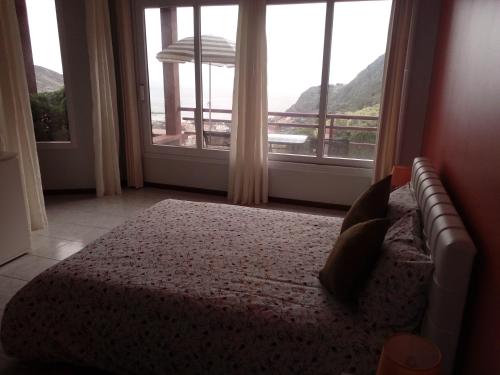 - une chambre avec un lit et une grande fenêtre dans l'établissement Moradia Cor de Rosa, à Machico