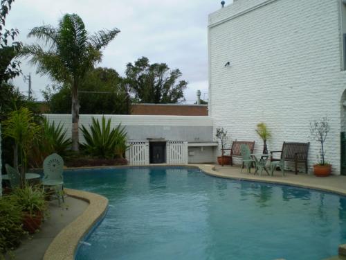 a swimming pool in a yard with chairs and a building at Banjo Paterson Motor Inn in Lakes Entrance