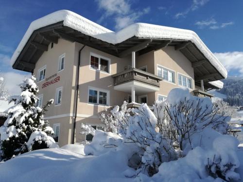 a building covered in snow with trees and bushes at Appartements Oberhauser in Westendorf