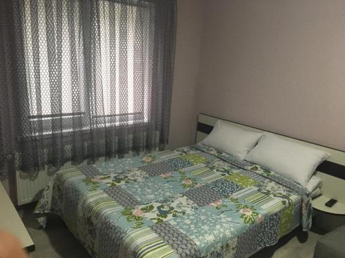 1 dormitorio con 1 cama con edredón en Guest House MAX, en Khmelʼnytsʼkyy