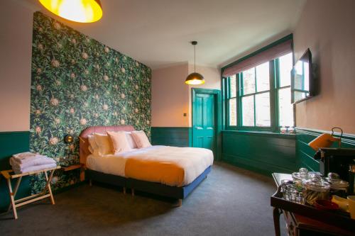 een slaapkamer met een bed en een groene muur bij The Ship Rooms in Londen