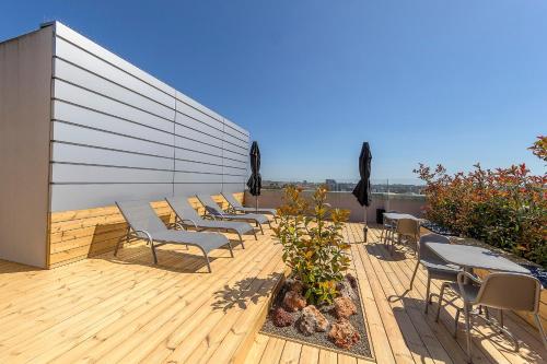 a deck with chairs and tables on top of a building at Serviced Apartments Boavista Palace in Porto