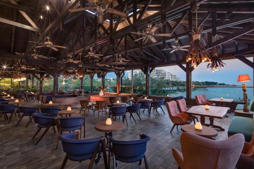 a restaurant with tables and chairs and a view of the water at Merit Crystal Cove Hotel Casino & SPA in Kérynia