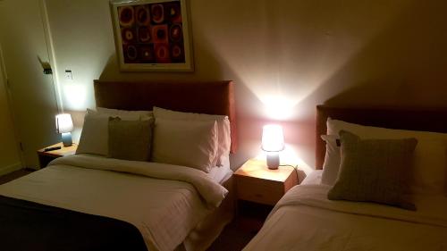 two beds in a room with two lamps on tables at The Auld Triangle in Loughrea