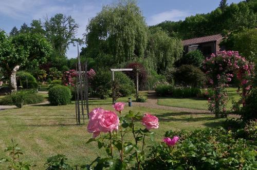 a garden with pink flowers in the grass at Les Glycines - Hôtel & Spa - Teritoria in Les Eyzies-de-Tayac