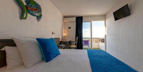 - une chambre avec un grand lit et un oreiller bleu dans l'établissement Hôtel Bellevue Cap d'Agde, au Cap d'Agde