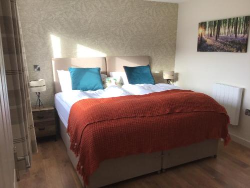 a bedroom with a bed with a red blanket and blue pillows at The Grange Silverstone in Towcester