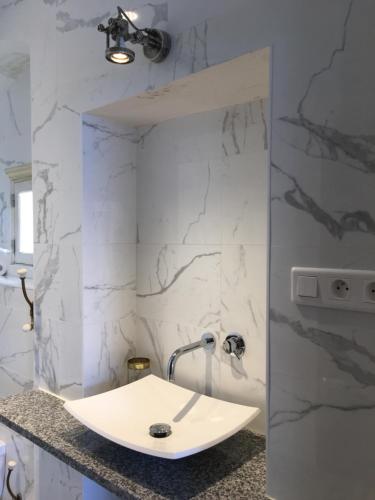 La salle de bains est pourvue d'un lavabo blanc et de murs en marbre. dans l'établissement Le Balcon du Pêcheur, à Calvi