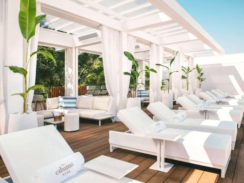 a room with white chairs and tables and windows at Sofitel Noosa Pacific Resort in Noosa Heads