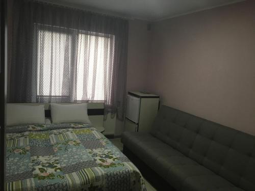 - une petite chambre avec un lit et un canapé dans l'établissement Guest House MAX, à Khmelnytsky