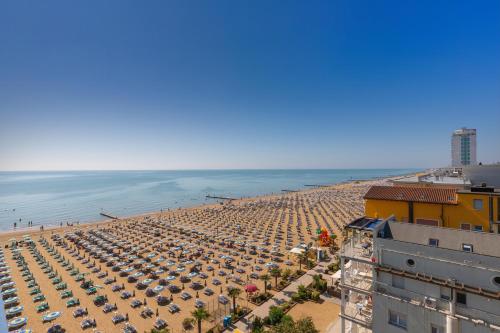 a beach with a lot of umbrellas and the ocean at Hotel Napoleon in Lido di Jesolo